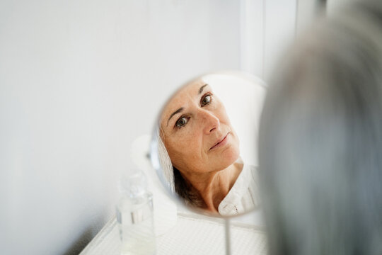 Mature woman looking at herself in table mirror