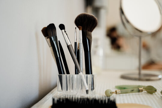 Detail of makeup brushes and cosmetics on table
