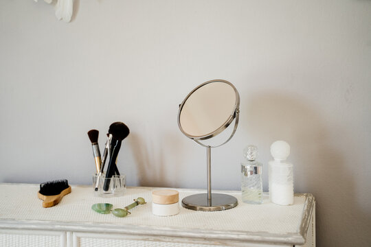 Detail of makeup brushes mirror and cosmetics on table