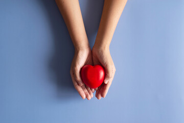 Hands people holding red heart model on blue background,World heart day concept,Top view,Copy space for text