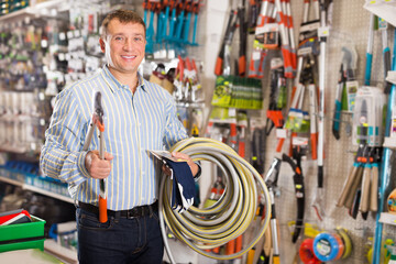 Obraz premium Man choosing new secateurs at a garden equipment shop
