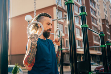 Young man doing pull ups on training apparatus