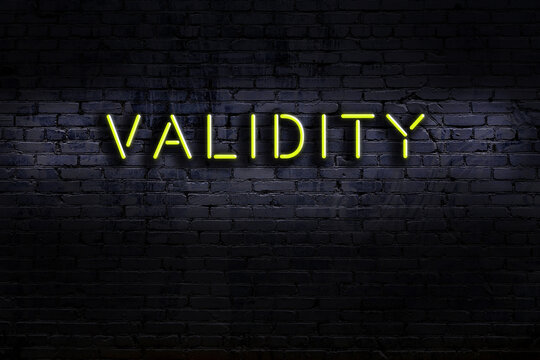 Neon sign. Word validity against brick wall. Night view