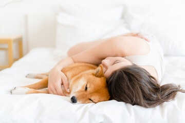 Woman cuddle dog in bed