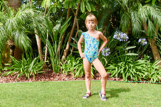 Little girl in a swimsuit standing in her yard