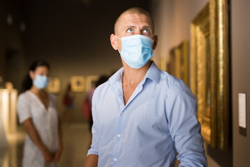 European man with mask admiring art work in museum