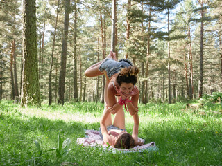 Laughing friends practicing acro yoga on meadow