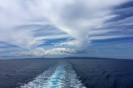 clouds in the sky over a body of water from back of boat