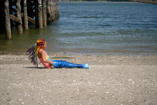 Girl's braids fly as she struggles into mermaid tail 
