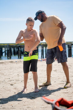 Father helps son apply sunscreen