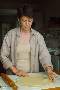 Woman Rolls Out Dough On A Baking Rug In The Kitchen