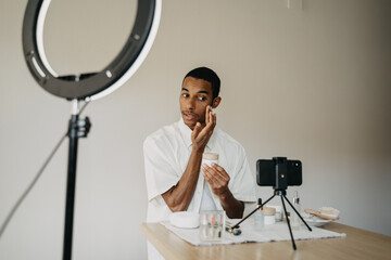 Young man doing beauty routine video tutorial at home