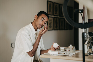 Young man doing beauty routine video tutorial at home