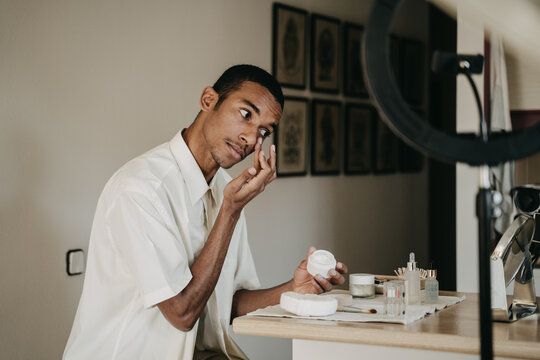 Young man doing beauty routine video tutorial at home