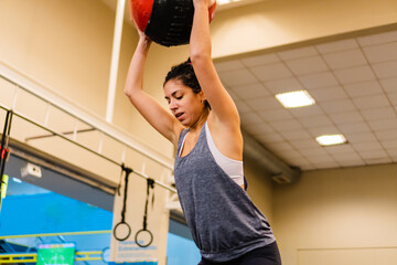 young hispanic latina woman in a gym ball throwing with a heavy ball
