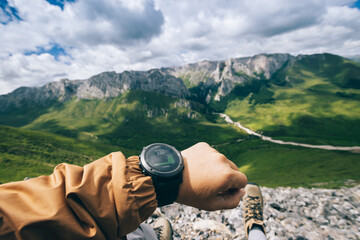 Hiker on high altitude mountain top checking the altimeter on the sports watch - obrazy, fototapety, plakaty