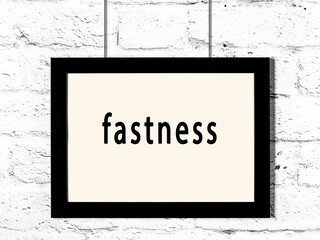 Black frame hanging on white brick wall with inscription fastness