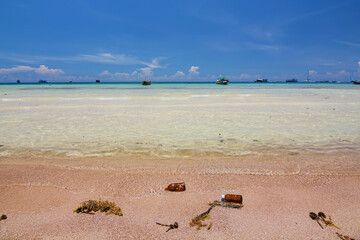 Thailand travel island Koh Tao with bottle garbage on sand beach and turquoise sea water with peace clear blue sky landscape background