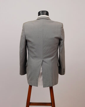 Men's formal suit in plain gray isolated on plain white background. A suit with a natural shape on a black mannequin. View from behind. Black suit mockup. Free space for your ad. Fashionable and cool.