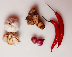Garlic, Shallots, Laos and Red chilies neatly arranged on a white background. Indonesian spices and...