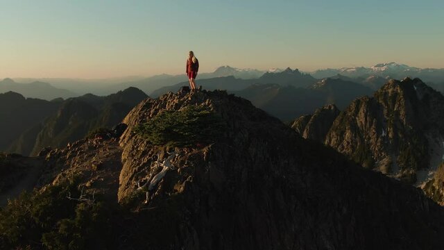 Adventurous Caucasian Woman Hiking on top of a Rocky Mountain Cliff. Sunny Summer Sunset. Mnt Brunswick Hike, North of Vancouver, British Columbia, Canada.
