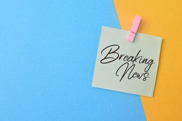 Paper note with phrase BREAKING NEWS isolated on yellow and blue background