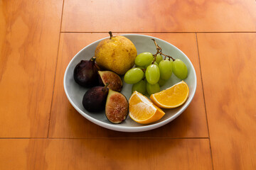Pear, grapes, orange and fig in a bowl heroe shot