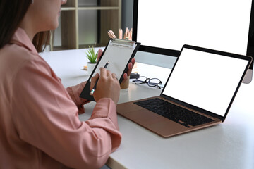Obraz na płótnie Canvas Businesswoman holding notebook and working with modern gadget.