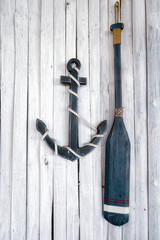 Composition on the marine theme with anchor and paddle on old white wooden background