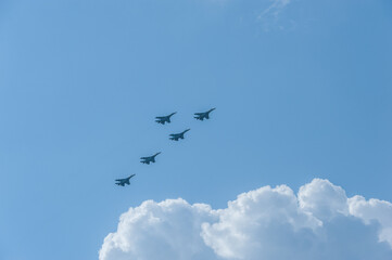 Military planes are flying in the blue sky above white clouds