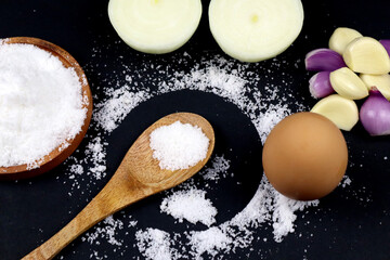 Flat lay vintage wooden spoon and has salt onions egg on it in black background