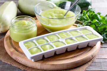 Zucchini puree in ice cube trays ready for freezing on a cutting board on a table. Frozen Food Concept.