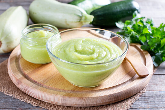 Zucchini puree on a background of fresh zucchini. Baby food for the first feeding. Healthy squash puree in a glass jar
