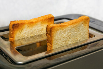 Slices of bread are prepared for breakfast. The toaster has two crispy toasters