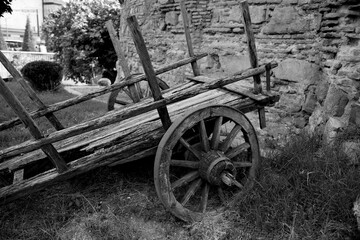 Fototapeta na wymiar An old wooden cart against the background of an ancient fortress wall.