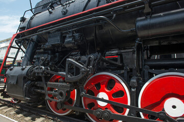Fototapeta na wymiar Eliminations of an old Russian steam locomotive. Black steam locomotive, red wheels.