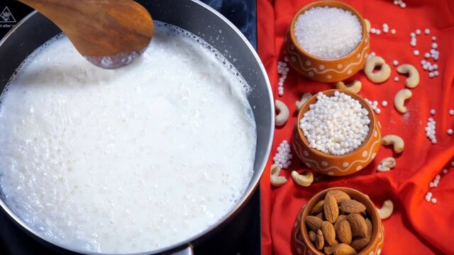 Hot milk mixed with white tapioca pearls on a gas stove - Indian dessert for festival food. Almonds  sabudana  cashew nuts  and sugar decorated in earthen pots in the kitchen