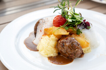 Meatball from minced beef with cucumber vegetables, mashed potatoes and sauce, garnished with tomato, herbs and sprouts on a white plate, modern gourmet dish, selected focus