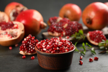 Delicious ripe pomegranate kernels in bowl on black table