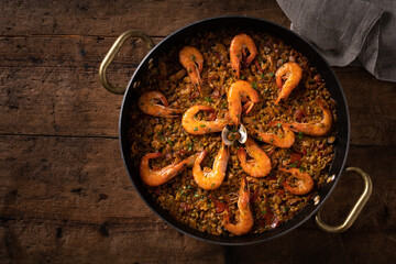 Valencian paella in the pan over wooden table. view from top