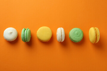 Concept of tasty dessert with macarons on orange background