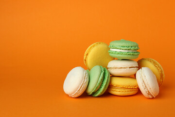 Concept of tasty dessert with macarons on orange background