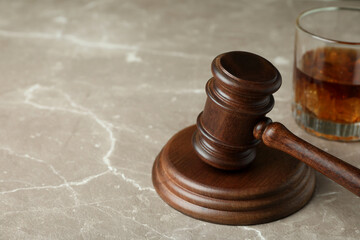 Judge gavel and glass of whiskey on gray textured table