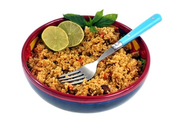 Taboulé au curry avec des rondelles de citron et des feuilles de menthe servi dans une assiette en gros plan sur fond blanc