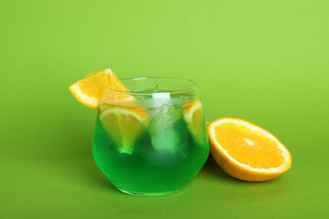 Fototapeta na wymiar Glass of citrus cocktail and ingredients on green background