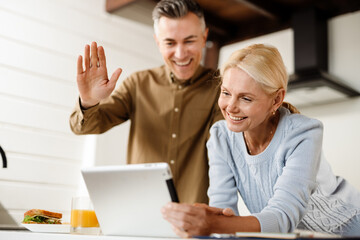 Smiling mid aged couple on a video call via digital tablet