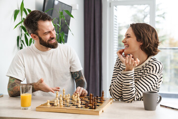 Happy young white couple playing chess