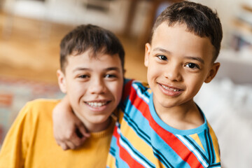 White two boys hugging and smiling at camera while posing at home