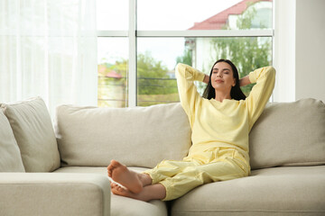 Fototapeta premium Young woman relaxing on sofa at home, space for text