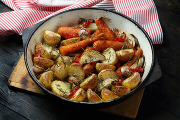Oven baked potatoes, carrots, garlic, onions with chili, thyme and rosemary
